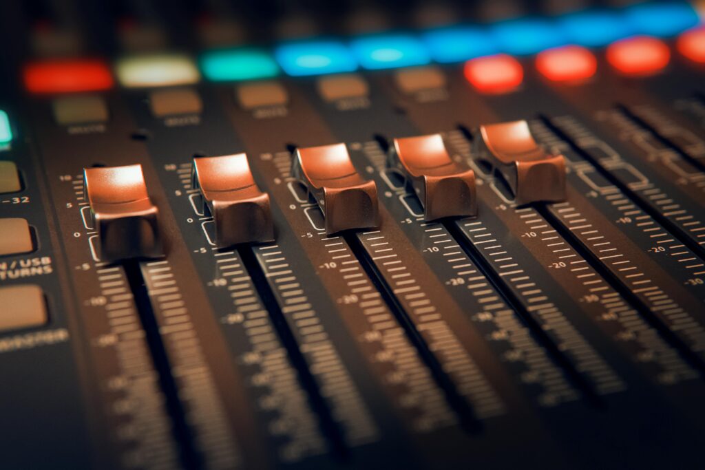 pexels-photo-3784424-3784424 Detailed close-up of an audio mixer with illuminated controls in a studio setting.